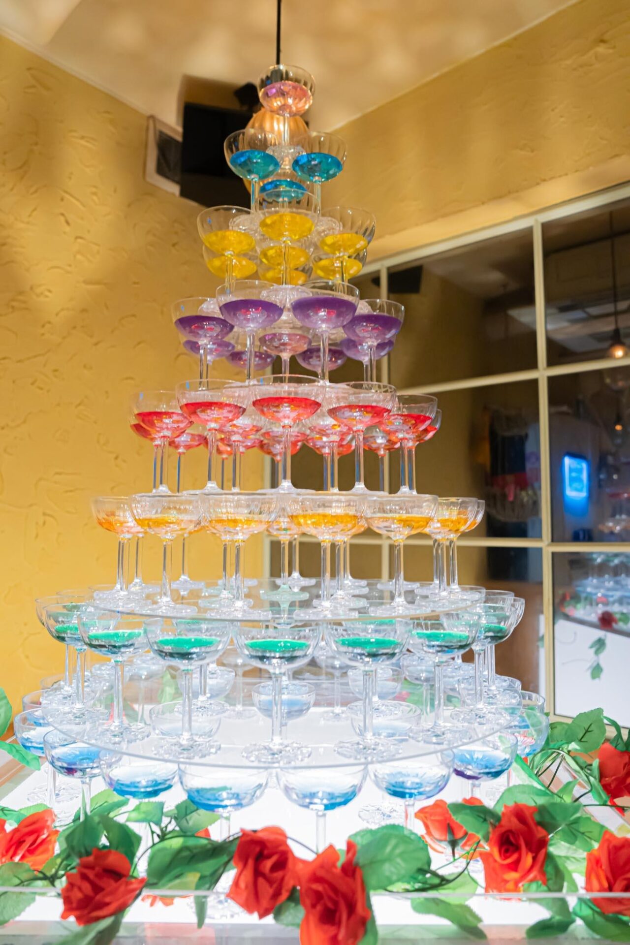 Vibrant rainbow-colored round champagne tower, colorfully changing colors at each level